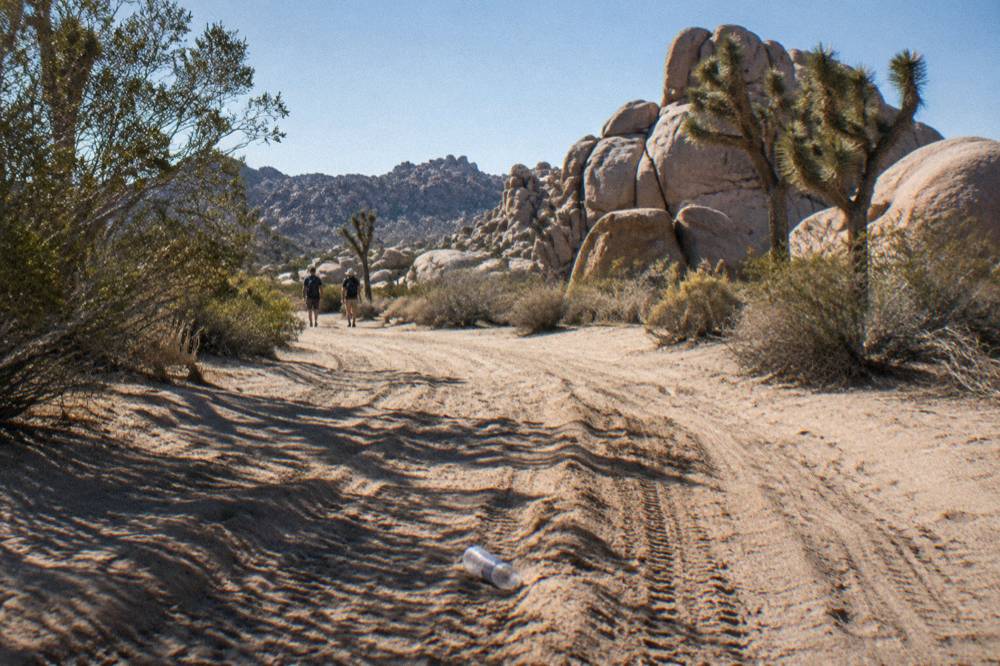 Dirt side road winding between tall granite formations in open desert