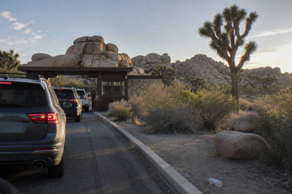 Line of cars waiting at a desert park entrance station in late afternoon light