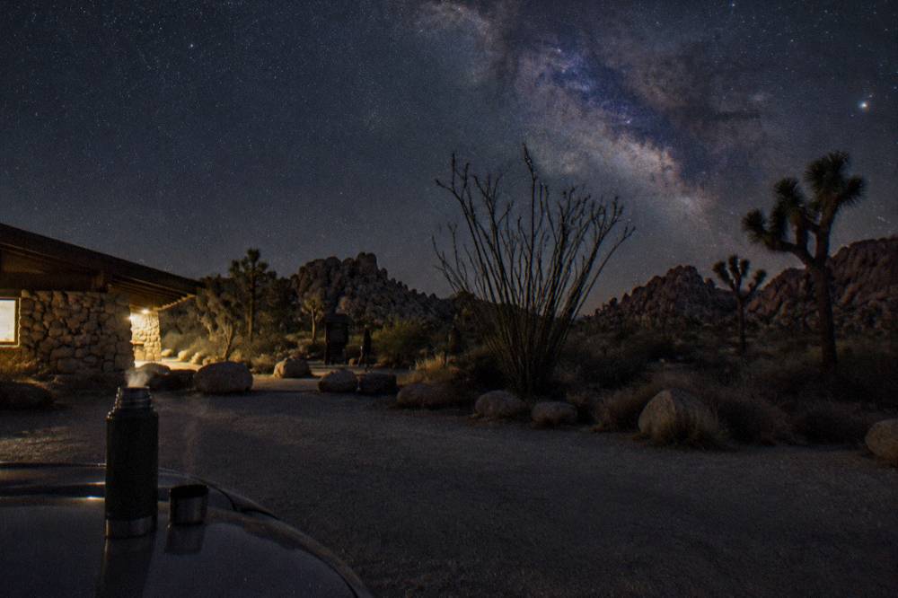 A dark desert sky filled with stars above silhouetted rock formations