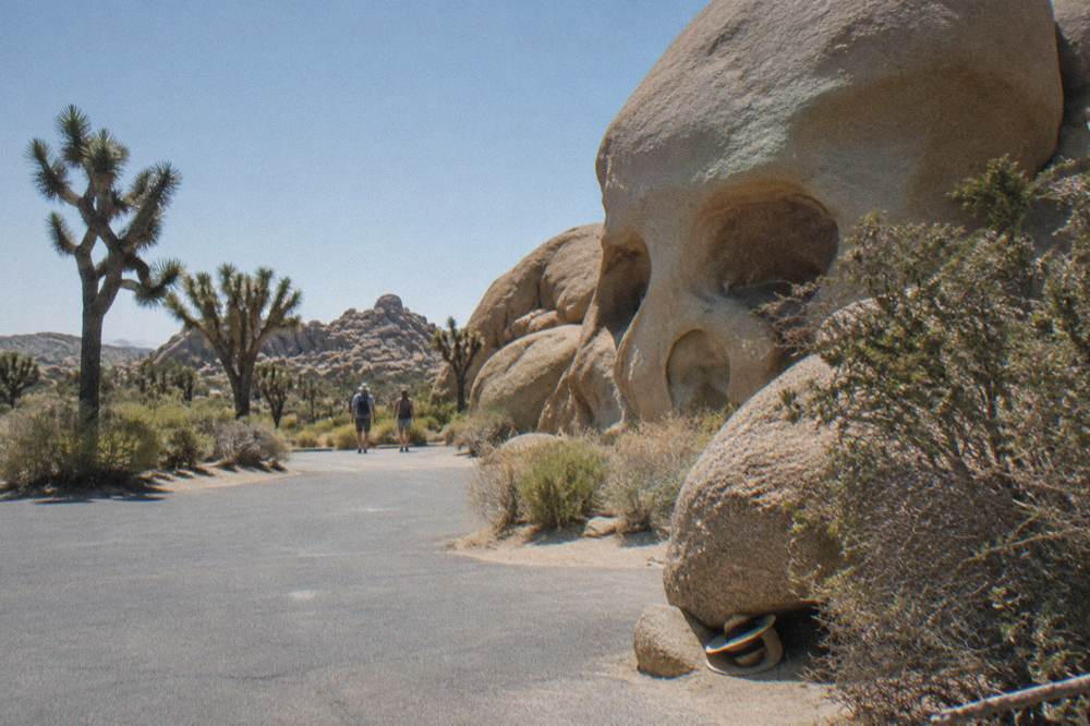 Sunlight falling on rock formations and a nearly empty parking area at a park pullout