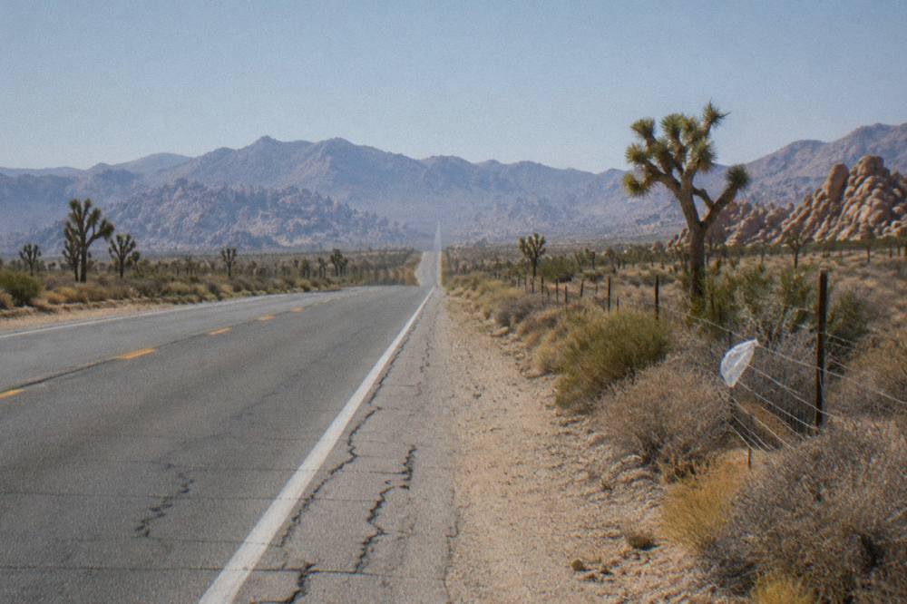 Open highway cutting through open desert toward distant mountains