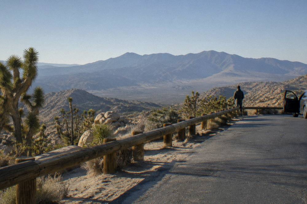 Desert road stretching toward a rocky mountain ridge under clear sky