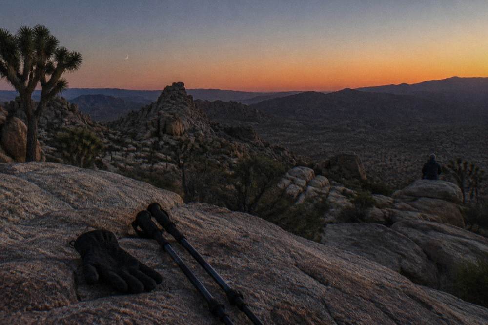 A crescent moon hanging low over dark desert rocks at dusk