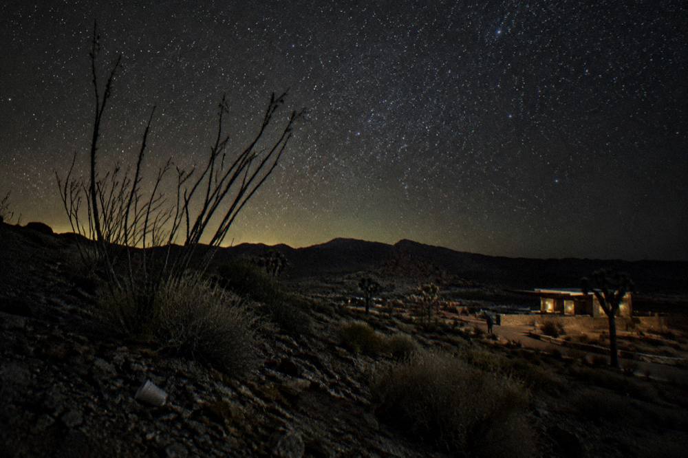 Dark desert horizon with a bright star field above rock formations
