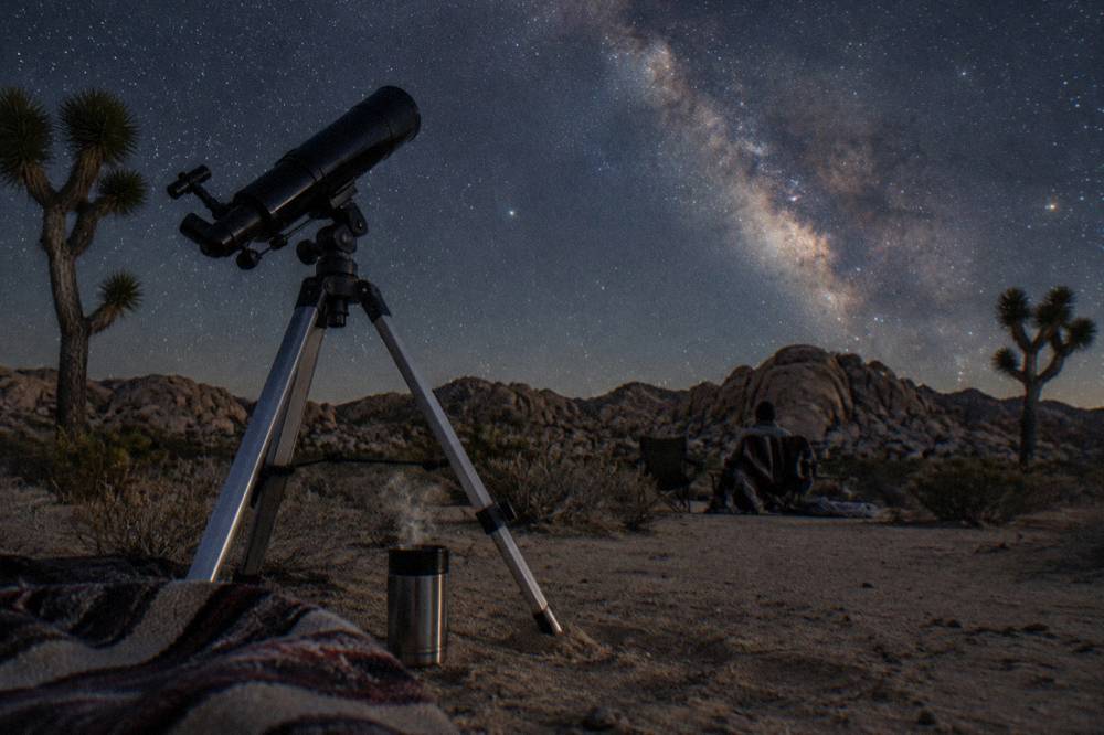 Telescope silhouetted against a star-filled desert sky at night