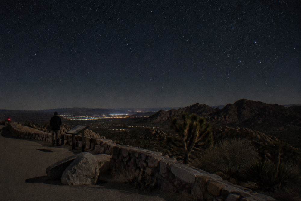 A dark desert sky filled with stars above silhouetted rock formations