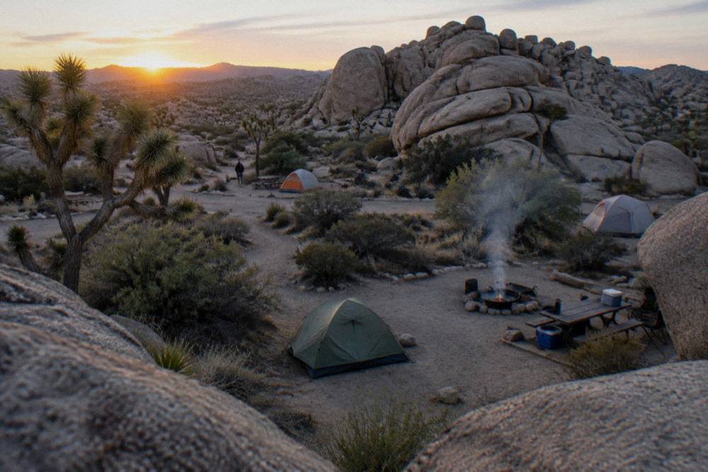 A small desert campground with a fire ring and rocks close around a few campsites